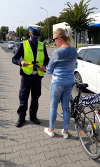 Policjant ruchu drogowego daje opaskę odblaskowa kobiecie na rowerze