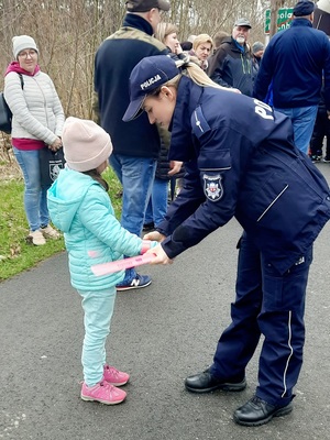 policjantka wręczająca małej dziewczynce element odblaskowy