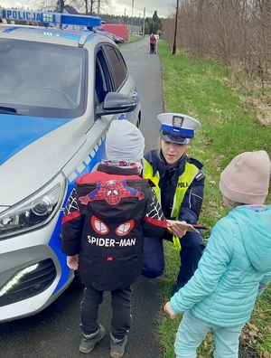 policjantka wręczająca małemu chłopcu element odblaskowy