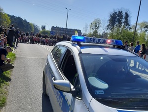 ulica, radiowóz , dwóch policjantów, w tle biegacze