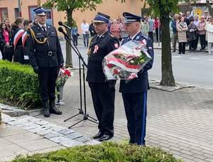 policjant i strażak w umundurowaniu galowym, policjant trzyma bukiet kwiatów