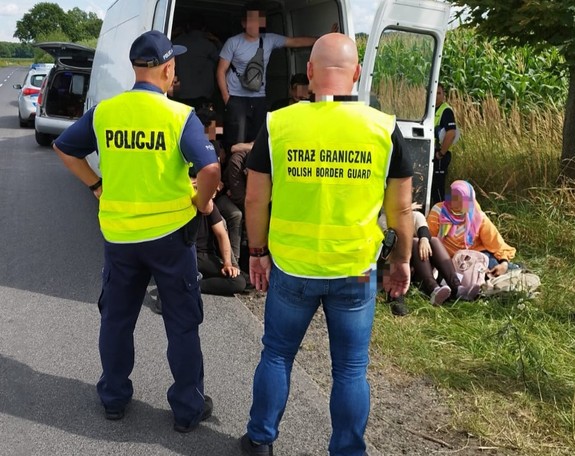 policjant i strażnik straży granicznej, uchodźcy w pojeździe typu bus