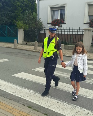 policjantka przechodzi przez przejście dla pieszych z dziewczynką