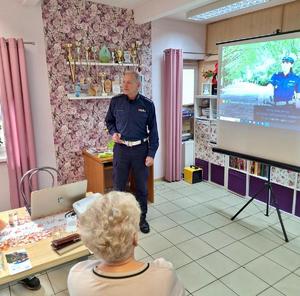 Zdjęcie przedstawia funkcjonariusza, który przeprowadza prelekcję dotyczącą bezpieczeństwa w ruchu drogowym.