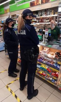 Dwie policjantki rozmawiają z ekspedientką sklepu na temat obostrzeń związanych z pandemią koronawirusa