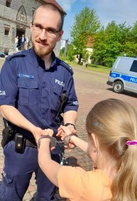 policjant,dziewczynka,która przymierza kajdanki