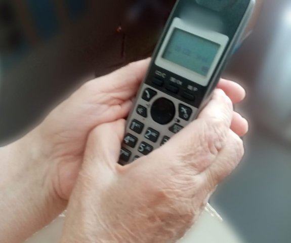 dłonie starszej osoby trzymające aparat telefoniczny